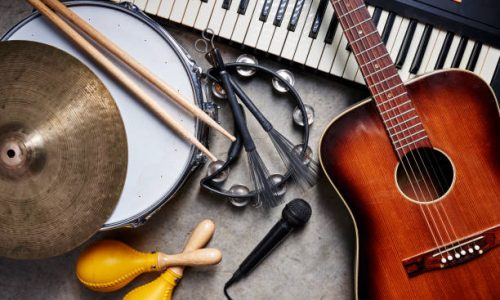 a group of musical instruments including a guitar, drum, keyboard, tambourine.